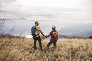 Mature man holding hands with woman standing on grass - UUF27675