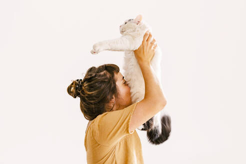 Frau hält Katze vor der Hauswand in die Höhe - MMPF00422