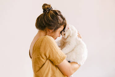 Frau spielt mit Katze vor der Wand zu Hause - MMPF00423