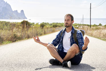 Man with eyes closed meditating on road - VEGF06044