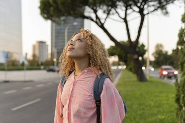 Thoughtful blond woman with backpack on street - JCCMF07670