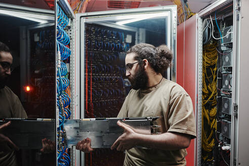 Techniker beim Einsetzen eines Maschinenteils in einen Server im Rechenzentrum - DSHF00589