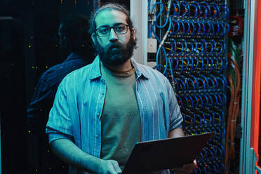 IT-Ingenieur mit Bart hält Laptop im Serverraum - DSHF00601