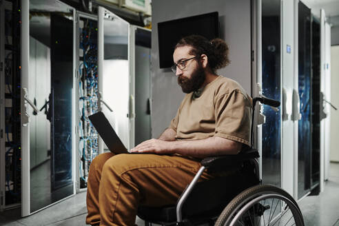 Techniker mit Behinderung arbeitet am Laptop im Serverraum - DSHF00608