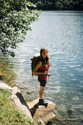 Woman with backpack standing on rock near Lake Levico - GIOF15571