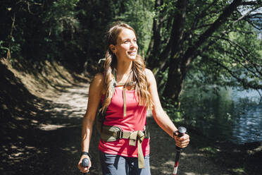 Lächelnde Frau beim Wandern am See an einem sonnigen Tag - GIOF15578