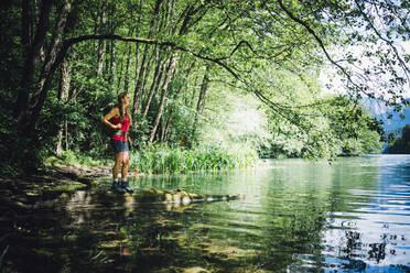 Hiker looking at Lake Levico standing under tree shade - GIOF15584