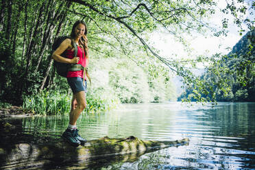 Happy woman standing on log at Lake Levico - GIOF15585