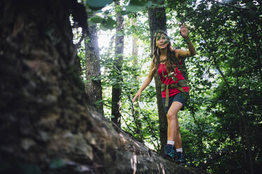 Curious hiker exploring forest walking on fallen tree - GIOF15591