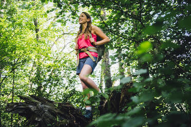 Smiling hiker standing amidst trees in forest - GIOF15594