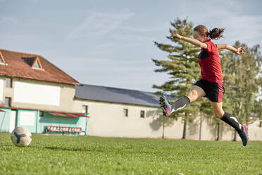 Mädchen springt auf Fußballplatz an sonnigem Tag - ZEDF04906