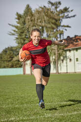 Glückliches Mädchen mit Rugby-Ball auf dem Spielfeld - ZEDF04914