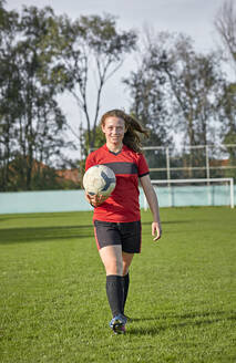 Glückliches Mädchen mit Fußball auf einem Feld - ZEDF04921