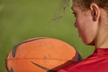 Mädchen hält Rugbyball auf einem Sportplatz - ZEDF04926