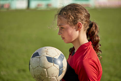 Nachdenkliches Mädchen mit Fußball an einem sonnigen Tag - ZEDF04927