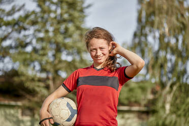 Glückliches Mädchen mit Fußball vor Bäumen stehend - ZEDF04930