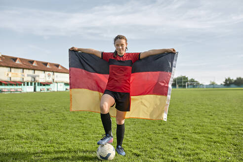 Mädchen mit deutscher Flagge auf einem Feld unter bewölktem Himmel stehend - ZEDF04932