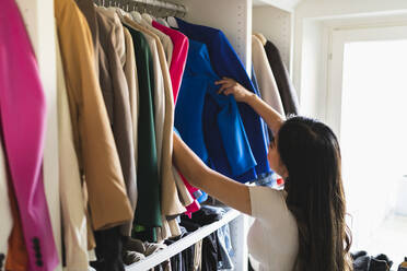 Frau wählt Kleidung im Kleiderschrank aus - DMMF00222