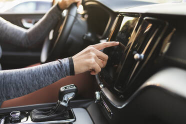 Frauenhand, die das im Auto sitzende Navigationsgerät kontrolliert - DMMF00252