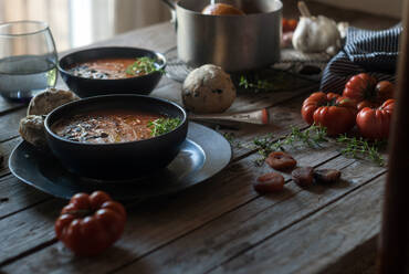 Zusammensetzung der servierten Schalen mit köstlichen Tomatencremesuppe mit Samen auf dem Tisch mit Tomaten und Brot Brötchen - ADSF39551