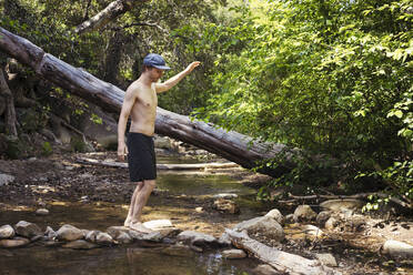 Mann ohne Hemd balanciert auf einem Felsen im Fluss - ACTF00263