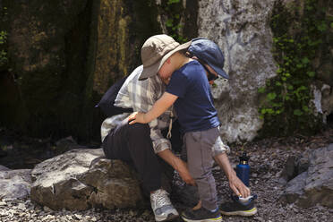 Vater hilft Sohn, Schuh auf Felsen zu tragen - ACTF00268