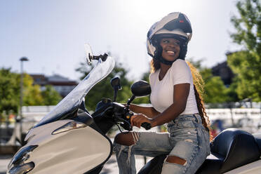 Glückliche junge Frau mit Helm auf einem Motorroller - OCMF02541