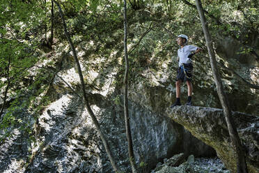 Junge mit verschränkten Armen auf einem Felsen im Wald stehend - DIKF00730