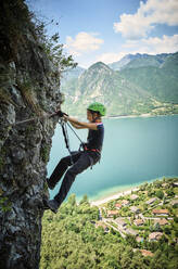 Girl climbing mountain with Lake Idro in background - DIKF00743
