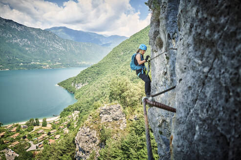Mature woman climbing mountain with Lake Idro in background - DIKF00744