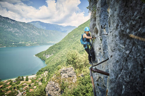 Woman wearing safety equipment climbing mountain - DIKF00745