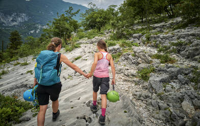 Frau hält die Hand ihrer Tochter beim Wandern auf einem Berg - DIKF00753