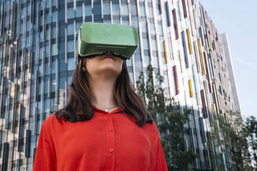 Young woman wearing virtual reality simulator in front of building - AMWF00878