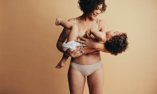Frau, die ihr Kind auf dem Arm trägt, liebevolle Mutter und Baby. - JLPSF10367