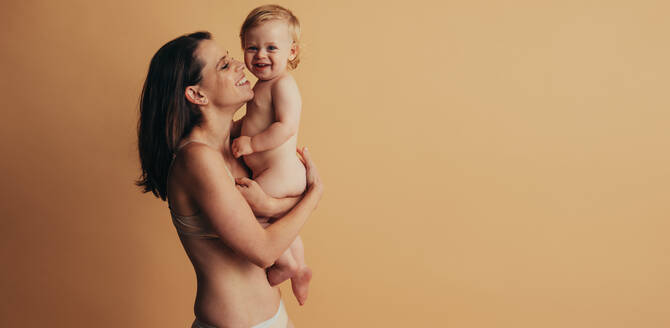 Eine Frau hält ihren Säugling hoch, eine gesunde Mutter und ihr Baby lächeln gemeinsam. - JLPSF10381