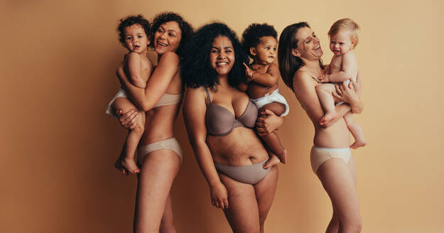 Group of mothers with babies. Women with postpartum bodies carrying their children looking at camera and smiling. - JLPSF10385