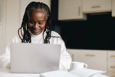 Reife Geschäftsfrau, die glücklich lächelt, während sie zu Hause auf einem Laptop tippt. Ältere Geschäftsfrau, die eine geschäftliche E-Mail sendet, während sie von zu Hause aus arbeitet. - JLPSF10441