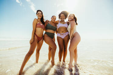 Glückliche Freundinnen stehen am Strand Wasser. Gruppe von fröhlichen jungen Frauen umarmt einander, während das Tragen von Badebekleidung am Strand. Sorglose Freundinnen Spaß haben während ihrer Sommerferien. - JLPSF10738