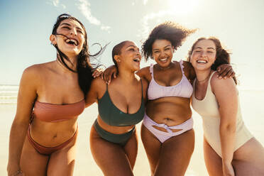 Eine Gruppe fröhlicher junger Frauen, die sich in Badekleidung am Strand umarmen. Sorglose Freundinnen, die Spaß haben und ihren Sommerurlaub genießen. - JLPSF10740