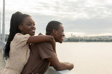 Nachdenkliche junge Frau steht mit ihrem Freund auf einer Brücke - JBUF00025