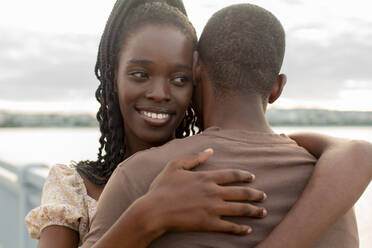 Smiling young woman embracing boyfriend at bridge - JBUF00027