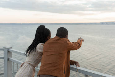 Junges Paar steht am Geländer und schaut auf den Fluss - JBUF00037