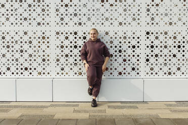 Woman wearing hooded shirt standing in front of wall - JBUF00058