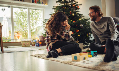 Eine kleine Familie, die an Weihnachten eine schöne Zeit miteinander verbringt. Eine liebevolle skandinavische Familie, die zu Hause am Weihnachtsbaum sitzt. - JLPSF10867