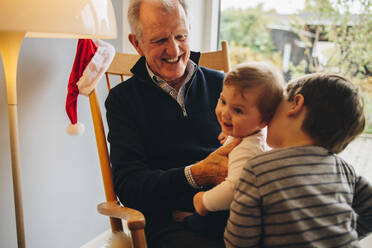 Zwei Jungen mit ihrem Großvater zu Weihnachten. Ein älterer Mann mit seinen beiden Enkeln zu Hause. - JLPSF10874
