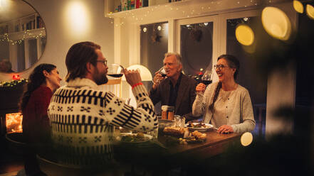 Europäische Familie sitzt am Tisch und trinkt Wein. Familie beim Thanksgiving-Essen zu Hause. - JLPSF10887