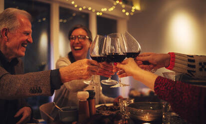 Eine glückliche Familie stößt mit Wein an und genießt das Abendessen an Heiligabend. Familie beim gemeinsamen Abendessen an Heiligabend. - JLPSF10888