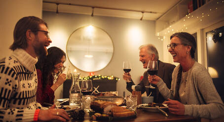 Glückliche Familie, die am Tisch sitzt, sich unterhält und Rotwein trinkt. Familie beim Weihnachtsessen zu Hause. - JLPSF10891