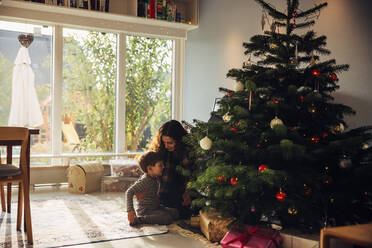 Mutter und Sohn sitzen zu Hause am Weihnachtsbaum. Mutter feiert mit ihrem Kind Weihnachten. - JLPSF10900
