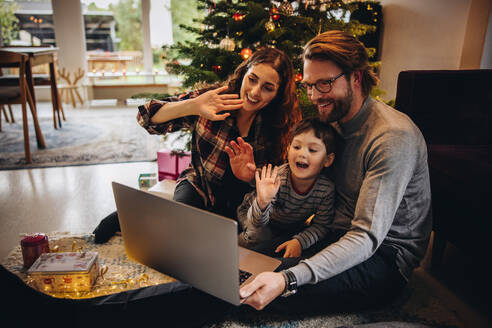 Eine Familie, die sich mit ihren Lieben online über einen Laptop verbindet und während der Weihnachtszeit einen Videoanruf von zu Hause aus tätigt. Weihnachtsfeier mit der Familie per Videokonferenz. - JLPSF10917